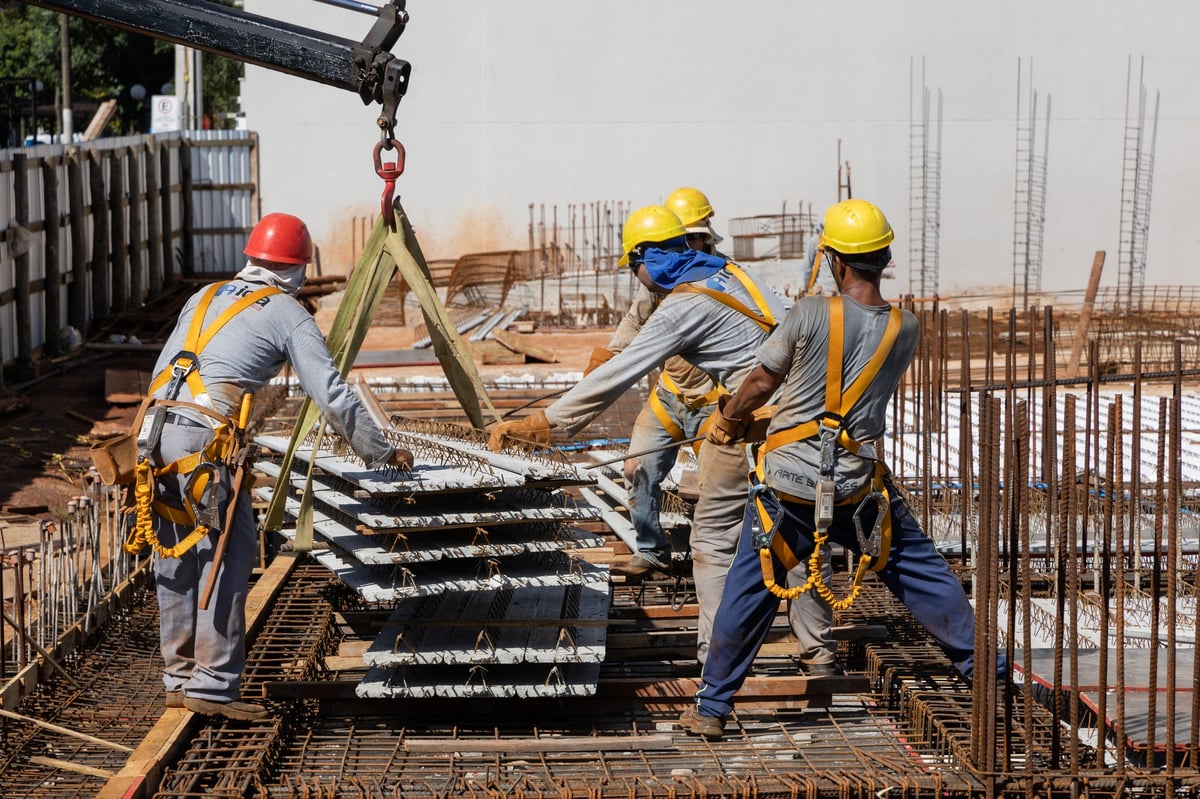 Men from the construction industry, working on the work of a building under construction. Placing slab pieces made with steel and concrete.
