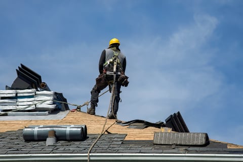 Construction worker applying roofing materials with pneumatic nailer